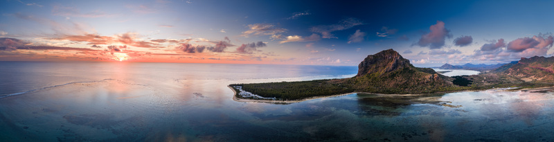 Aerial view of Le Morne Brabant mountain and the turquoise lagoon at sunset with coral reefs and a colorful sky in Mauritius Moka District Mauritius. Aerial view of Le Morne Brabant mountain and the turquoise lagoon at sunset with coral reefs and a colorful sky in Mauritius Moka District Mauritius.