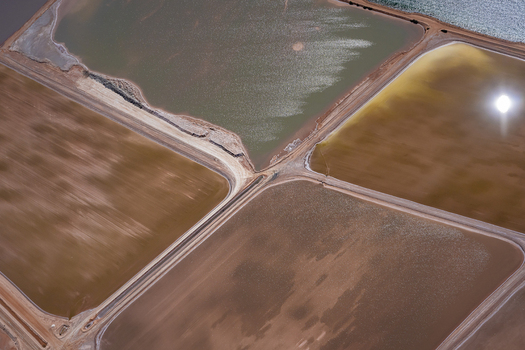 Aerial view of salt pans and industrial evaporation ponds showing varying shades of brown yellow and green mineral deposits separated by earthen embankments in Kalbarri Western Australia Australia. Aerial view of salt pans and industrial evaporation ponds showing varying shades of brown yellow and green mineral deposits separated by earthen embankments in Kalbarri Western Australia Australia.
