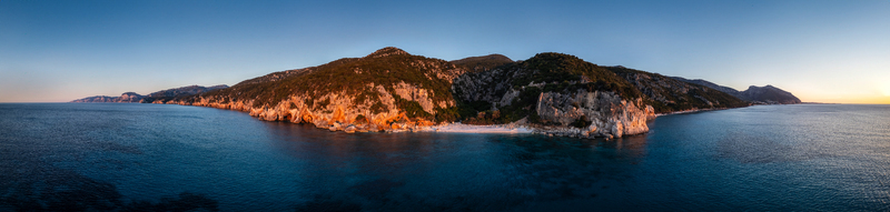 Aerial view of Spiaggia di Cala Fuili with rugged limestone cliffs and turquoise sea at sunset in Dorgali Sardegna Italy. Aerial view of Spiaggia di Cala Fuili with rugged limestone cliffs and turquoise sea at sunset in Dorgali Sardegna Italy.