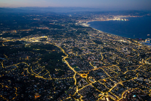 Aerial view of the illuminated city of Antibes at night featuring glowing street lights coastal roads and the Mediterranean coastline in Antibes Provence Alpes Cote d Azur France. Aerial view of the illuminated city of Antibes at night featuring glowing street lights coastal roads and the Mediterranean coastline in Antibes Provence Alpes Cote d Azur France.