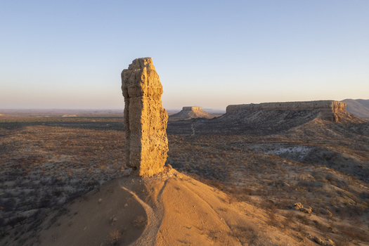 Aerial view of a towering rock formation standing proudly against the vast sun baked landscape near Ugab River Namibia. Aerial view of a towering rock formation standing proudly against the vast sun baked landscape near Ugab River Namibia.