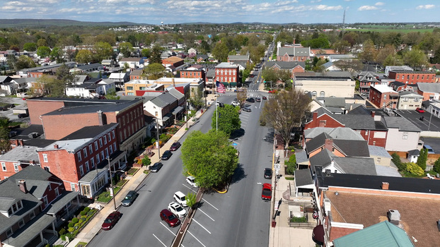 Aerial view of historic brick buildings a central street with parked cars and a prominent American flag in the town of Manheim Pennsylvania United States.
