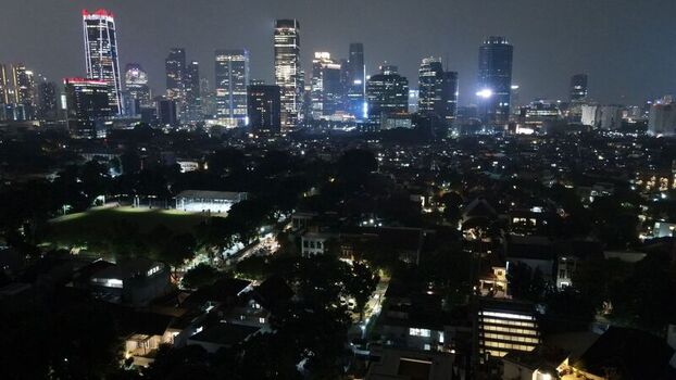 Aerial view of the illuminated Jakarta skyline at night with modern skyscrapers rising above the residential neighborhoods and dark tree lined streets in South Jakarta Jakarta Indonesia. Aerial view of the illuminated Jakarta skyline at night with modern skyscrapers rising above the residential neighborhoods and dark tree lined streets in South Jakarta Jakarta Indonesia.