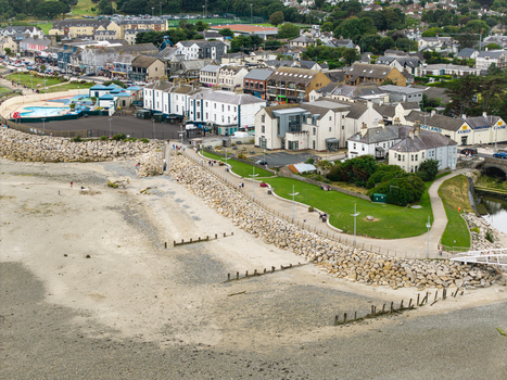 Aerial view of the coastal town of Newcastle featuring a sandy beach stone seawall green parkland and buildings along the waterfront in Newcastle Northern Ireland United Kingdom. Aerial view of the coastal town of Newcastle featuring a sandy beach stone seawall green parkland and buildings along the waterfront in Newcastle Northern Ireland United Kingdom.