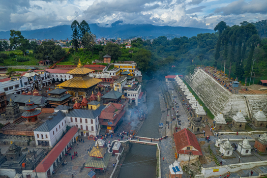 Aerial view of Pashupatinath Temple with its golden roof stone shrines and cremation ghats along the Bagmati River in Nepal.