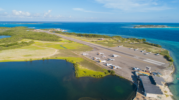 Aerial view of Los Roques archipelago airport with small planes on the tarmac surrounded by turquoise sea and green vegetation in Los Roques Dependencias Federales Venezuela. Aerial view of Los Roques archipelago airport with small planes on the tarmac surrounded by turquoise sea and green vegetation in Los Roques Dependencias Federales Venezuela.