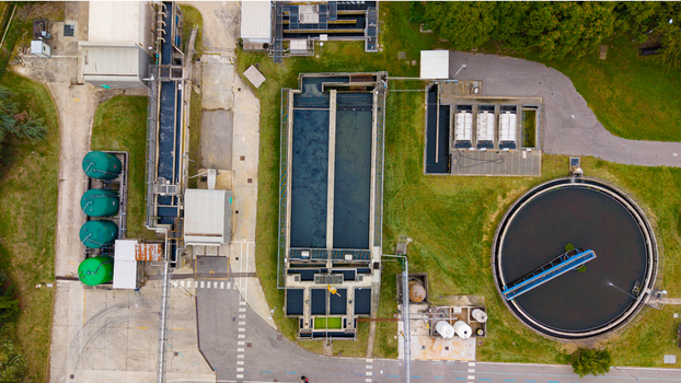 Aerial view of the wastewater treatment plant featuring circular sedimentation tanks rectangular filtration basins and green storage silos in Rancate Lombardia Italy. Aerial view of the wastewater treatment plant featuring circular sedimentation tanks rectangular filtration basins and green storage silos in Rancate Lombardia Italy.