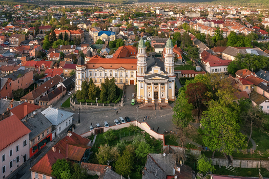 Aerial view of a majestic cathedral with twin towers amidst a tapestry of red roofed buildings and verdant trees Uzhhorod Zakarpattia Oblast Ukraine. Aerial view of a majestic cathedral with twin towers amidst a tapestry of red roofed buildings and verdant trees Uzhhorod Zakarpattia Oblast Ukraine.