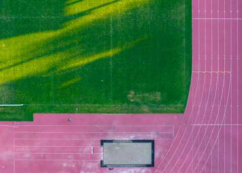 Aerial view of the Sports and Recreation Center featuring a green grass field and a red running track with a long jump pit in Starogard Gdanski Pomeranian Voivodeshi Poland. Aerial view of the Sports and Recreation Center featuring a green grass field and a red running track with a long jump pit in Starogard Gdanski Pomeranian Voivodeshi Poland.