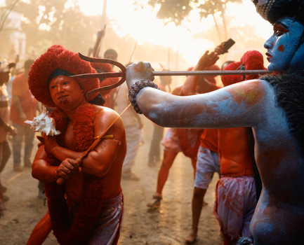 Munshiganj Bangladesh 13 April 2025 View of vibrant red painted figures in a piercing ritual their intense devotion stark against the hazy golden light and deep blue tones. Munshiganj Bangladesh 13 April 2025 View of vibrant red painted figures in a piercing ritual their intense devotion stark against the hazy golden light and deep blue tones.