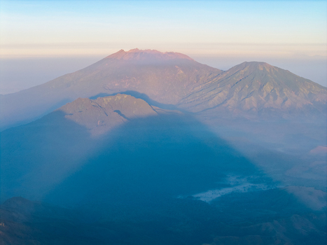 Aerial view of the Ijen volcano complex at sunrise with rugged peaks volcanic slopes and soft morning mist in Ijen East Java Indonesia.