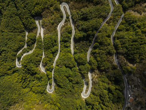 Aerial view of a winding serpentine road cutting through a dense green forest in the mountainous landscape of Savnik Savnik Municipality Montenegro. Aerial view of a winding serpentine road cutting through a dense green forest in the mountainous landscape of Savnik Savnik Municipality Montenegro.