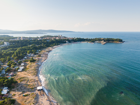 Aerial view of the coastline at Kiten featuring a sandy beach turquoise sea lush green trees and small buildings along the shore in Kiten Burgas Bulgaria. Aerial view of the coastline at Kiten featuring a sandy beach turquoise sea lush green trees and small buildings along the shore in Kiten Burgas Bulgaria.