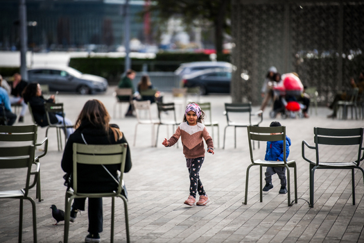 Zurich Switzerland 02 April 2023 View of a child dances amidst the chairs in the foreground while people relax at the National Museum Zurich in the soft afternoon light. Zurich Switzerland 02 April 2023 View of a child dances amidst the chairs in the foreground while people relax at the National Museum Zurich in the soft afternoon light.