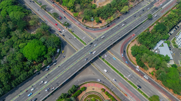 Aerial view of a multi level highway interchange with cars driving on asphalt roads surrounded by lush green trees and urban vegetation in Jakarta Indonesia. Aerial view of a multi level highway interchange with cars driving on asphalt roads surrounded by lush green trees and urban vegetation in Jakarta Indonesia.