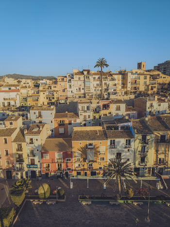 Aerial view of colorful traditional houses and palm trees under a clear blue sky in the historic center of La Vila Joiosa Valencian Community Spain. Aerial view of colorful traditional houses and palm trees under a clear blue sky in the historic center of La Vila Joiosa Valencian Community Spain.