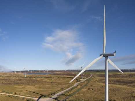 Aerial view of wind turbines at Eaglesham moor standing across the vast moorland landscape under a clear blue sky Kilmarnock Scotland United Kingdom.