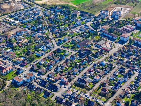 Aerial view of rooftops painted with vibrant hues amidst the geometric precision of planned streets and the surrounding nature Sausheim Grand Est France.