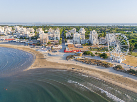 Aerial view of the coastal town with its distinctive pyramid shaped apartment buildings sandy beach and a large Ferris wheel in La Grande Motte Occitanie France.