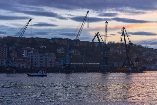 Pasai Donibane Spain 09 March 2026 View of Puerto Pasajes with industrial cranes silhouetted against a twilight sky and a small boat on the water. Pasai Donibane Spain 09 March 2026 View of Puerto Pasajes with industrial cranes silhouetted against a twilight sky and a small boat on the water.