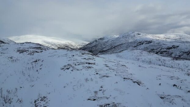 Aerial view of snowy mountains and people on Kvaloya Norway.
