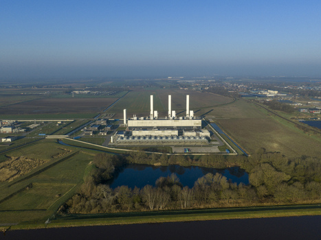 Aerial view of the nitrogen plant with tall white chimneys and industrial structures surrounded by flat green fields and a small pond Zuidbroek Groningen Netherlands. Aerial view of the nitrogen plant with tall white chimneys and industrial structures surrounded by flat green fields and a small pond Zuidbroek Groningen Netherlands.