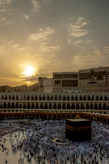 Aerial view of Masjid al Haram with the Kaaba surrounded by crowds of pilgrims under a golden sunset sky in Makkah Makkah Province Saudi Arabia. Aerial view of Masjid al Haram with the Kaaba surrounded by crowds of pilgrims under a golden sunset sky in Makkah Makkah Province Saudi Arabia.