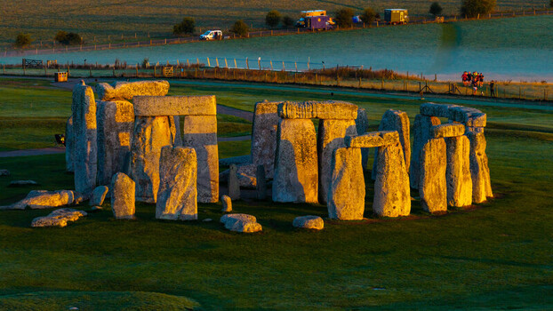 Aerial view of Stonehenge illuminated by the warm golden light of sunrise surrounded by the lush green landscape of the Salisbury Plain in Salisbury England United Kingdom. Aerial view of Stonehenge illuminated by the warm golden light of sunrise surrounded by the lush green landscape of the Salisbury Plain in Salisbury England United Kingdom.