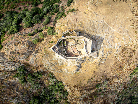 Aerial view of Castello del Volterraio an ancient stone fortress on a rocky hill surrounded by rugged terrain and Mediterranean scrub in Portoferraio Toscana Italy.