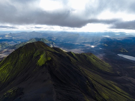 Aerial view of dramatic light piercing through heavy clouds over rugged moss covered mountains and serene lakes Landmannalaugar Iceland. Aerial view of dramatic light piercing through heavy clouds over rugged moss covered mountains and serene lakes Landmannalaugar Iceland.