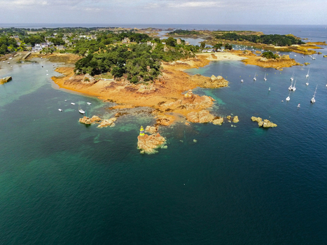 Aerial view of the lighthouse at Brehat surrounded by rocky coastline turquoise waters and sailboats in Ile de Brehat Brittany France.