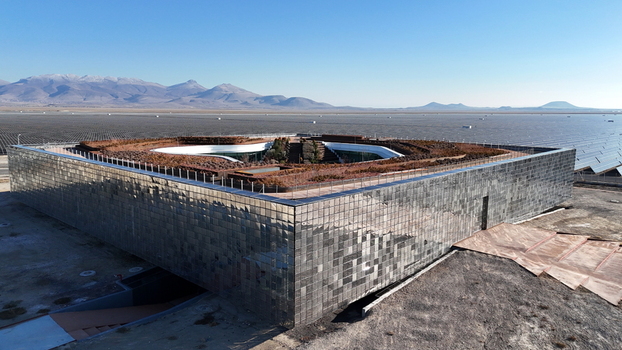 Aerial view of the Karapinar Solar Power Plant with a modern reflective building and green roof surrounded by vast solar panel arrays in Karapinar Konya Turkiye.