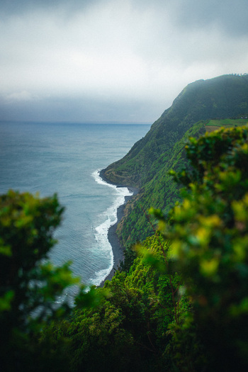 Aerial view of rugged cliffs meet the churning sea a symphony of green foliage against the dark volcanic rock Azores Azores Portugal.