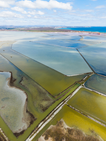 Aerial view of the colorful salt evaporation ponds of Lake Atanasovsko with narrow dikes and the Black Sea coast under a cloudy sky in Burgas Burgas Bulgaria. Aerial view of the colorful salt evaporation ponds of Lake Atanasovsko with narrow dikes and the Black Sea coast under a cloudy sky in Burgas Burgas Bulgaria.