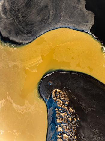 Aerial view of volcanic black sand contrasting with vibrant yellow mineral rich water in a geothermal landscape in Reykjanesbaer Iceland. Aerial view of volcanic black sand contrasting with vibrant yellow mineral rich water in a geothermal landscape in Reykjanesbaer Iceland.