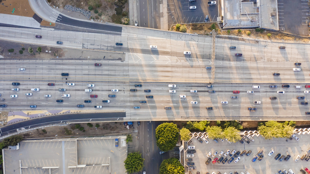 Aerial view of a busy freeway interchange with multiple lanes of traffic and adjacent parking lots in Los Angeles California United States.
