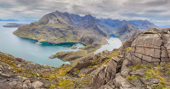 View of Sgurr na Stri overlooking the dark waters of Loch Coruisk surrounded by rugged mountain peaks and rocky terrain in Isle of Skye Scotland United Kingdom. View of Sgurr na Stri overlooking the dark waters of Loch Coruisk surrounded by rugged mountain peaks and rocky terrain in Isle of Skye Scotland United Kingdom.