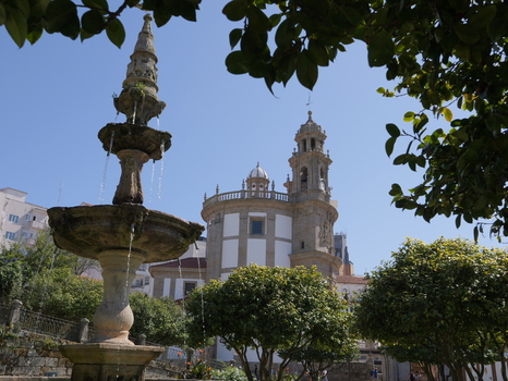 View of the historic Santuario de la Virgen Peregrina with a stone fountain in the foreground and lush green trees under a clear blue sky in Pontevedra Pontevedra Spain.