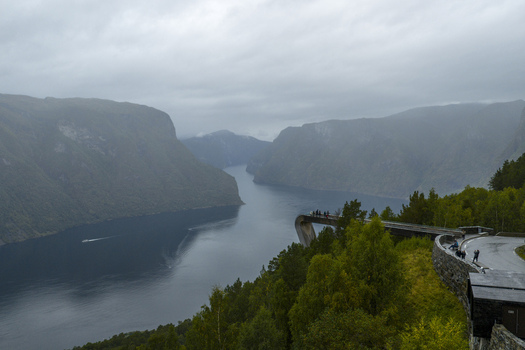 Aerial view of the Stegastein lookout platform extending over the Aurlandsfjord with tourists and misty mountains in Aurland Vestland Norway.