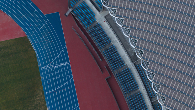 Aerial view of Kaohsiung National Stadium featuring the blue running track seating rows and solar panel roof in Juguang Village Kaohsiung City Taiwan.