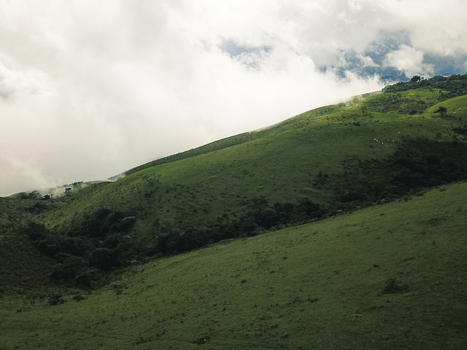 Aerial view of lush green hills shrouded in ethereal mist under a dramatic sky Obudu Cross River Nigeria.