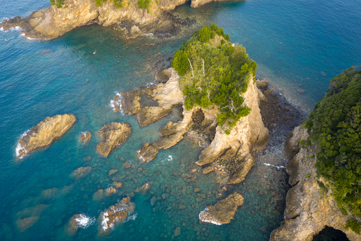 Aerial view of rocky islands with lush green vegetation surrounded by clear turquoise water along the rugged coastline Izu Shizuoka Japan. Aerial view of rocky islands with lush green vegetation surrounded by clear turquoise water along the rugged coastline Izu Shizuoka Japan.