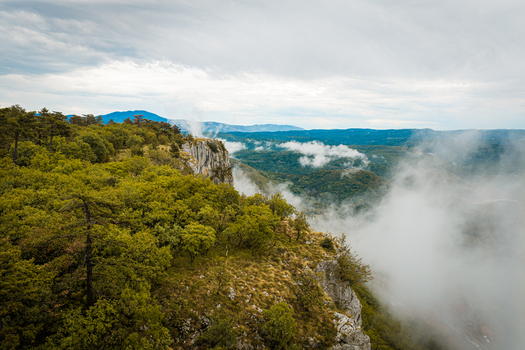 Aerial view of the forested cliffs and rocky terrain of Istria County shrouded in mist under a cloudy sky in Buzet Istria County Croatia.