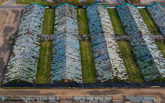 Aerial view of long rows of abandoned greenhouses with weathered glass roofs and green grass in Vilnius County Lithuania. Aerial view of long rows of abandoned greenhouses with weathered glass roofs and green grass in Vilnius County Lithuania.