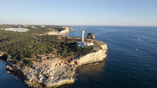 Aerial view of the Ponta do Altar Lighthouse situated on a rocky cliff overlooking the Atlantic Ocean in Ferragudo Faro District Portugal.