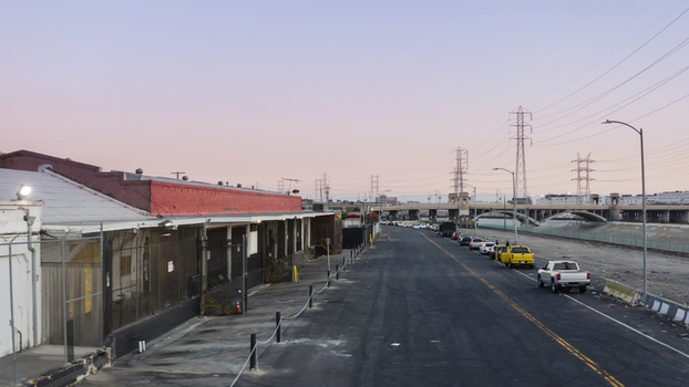 Aerial view of an industrial street alongside the Los Angeles River with parked cars power lines and a bridge in the distance in Los Angeles California United States. Aerial view of an industrial street alongside the Los Angeles River with parked cars power lines and a bridge in the distance in Los Angeles California United States.