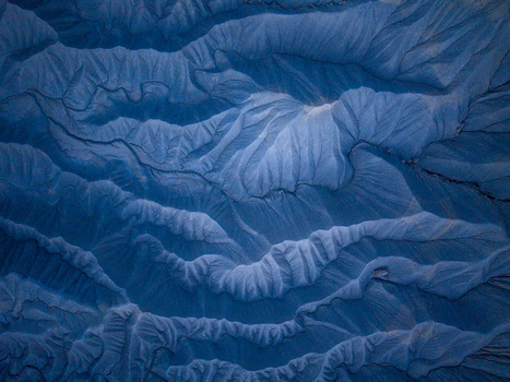 Aerial view of the intricate eroded blue toned badlands of Caineville showcasing dramatic ridges and deep gullies carved into the desert landscape in Caineville Utah United States. Aerial view of the intricate eroded blue toned badlands of Caineville showcasing dramatic ridges and deep gullies carved into the desert landscape in Caineville Utah United States.