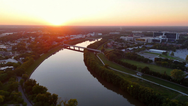 Aerial view of White River at sunset with a bridge spanning the water surrounded by lush trees and urban buildings in Indianapolis Indiana United States. Aerial view of White River at sunset with a bridge spanning the water surrounded by lush trees and urban buildings in Indianapolis Indiana United States.