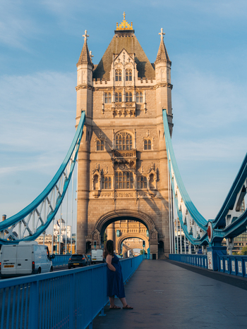 View of a lone figure on the vibrant blue walkway of Tower Bridge admiring the intricate stone tower glowing in warm light London England United Kingdom. View of a lone figure on the vibrant blue walkway of Tower Bridge admiring the intricate stone tower glowing in warm light London England United Kingdom.
