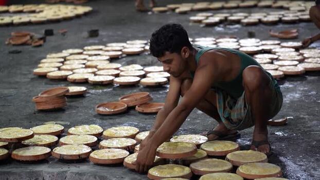 View of a man arranging traditional yogurt plates Bangladesh. View of a man arranging traditional yogurt plates Bangladesh.